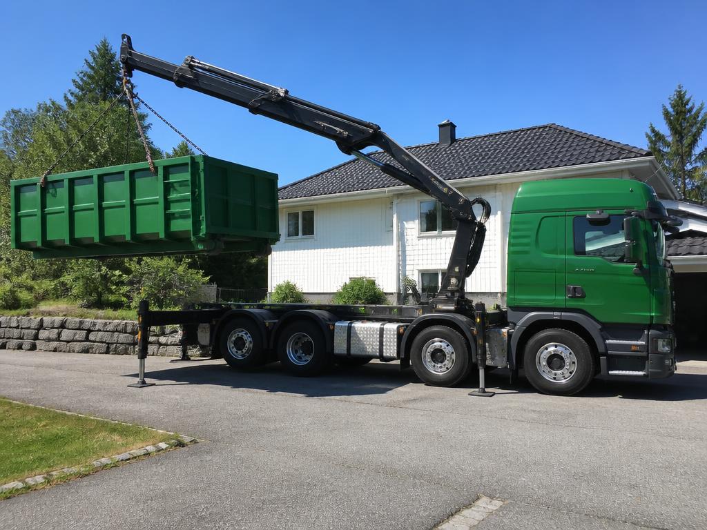 Grønn kranbil fra Nordik som løfter en container